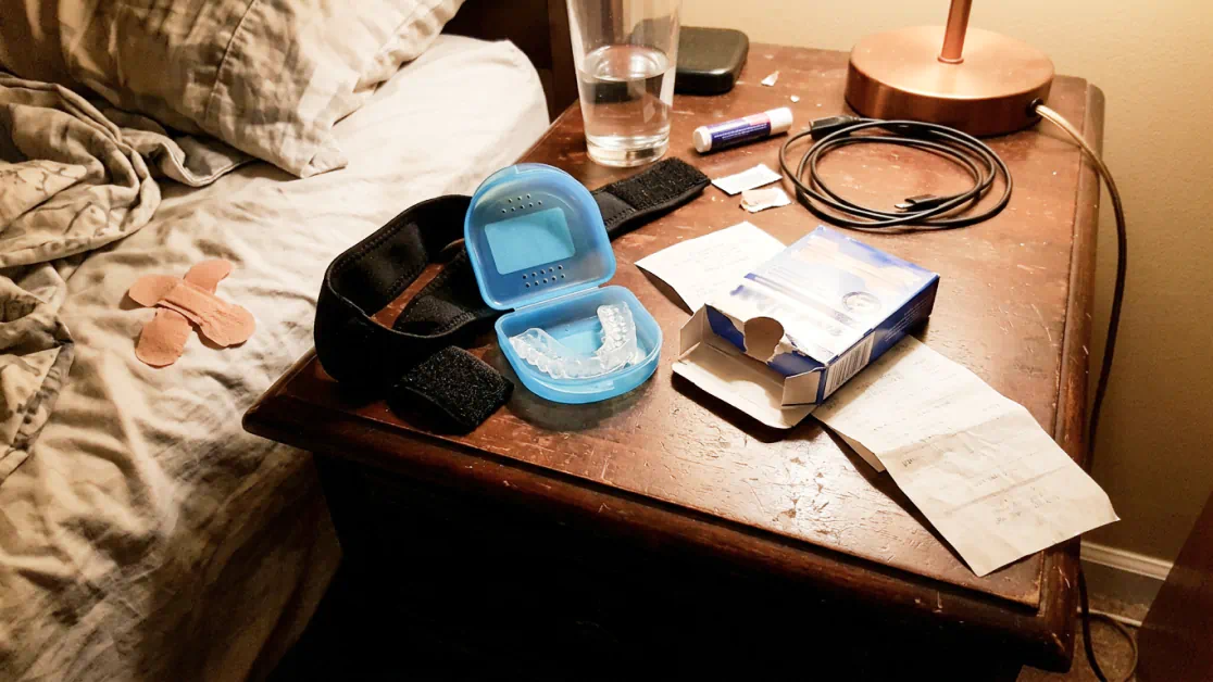 Nose strips, mouth guard and chin strap piled on a nightstand